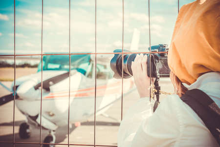 Spotter photographing a plane through the fence of Airportの写真素材