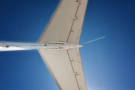 Tail of a jet airplane in front of sky background with flying airplane track, bottom viewの写真素材