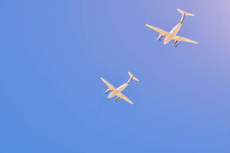 Two small aircrafts flying together in a blue skyの写真素材