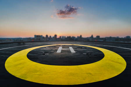 Helipad on the roof of a skyscraper after raining with cityscape view and sunsetの写真素材