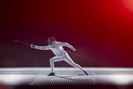 Fencing player isolated on the black red gradient backgroundの写真素材