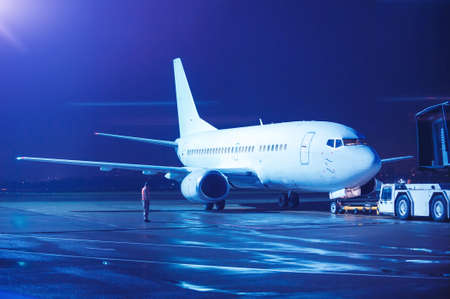 Airplane docked at the terminal and ready for takeoff. Modern international airport at night.の写真素材