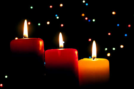 Three multi-coloured candles burn on a dark abstract backgroundの写真素材