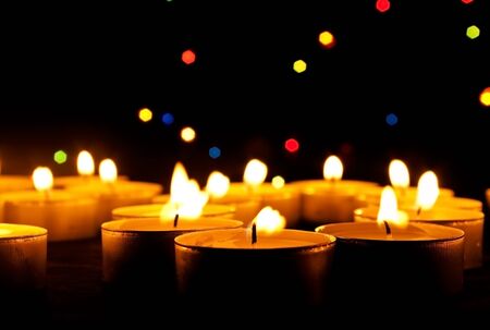 Tea candles burn on an abstract dark background の写真素材