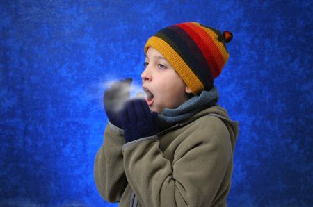 Child trying to warm his hands with his breath in winter outfit. Look at my gallery for more winter imagesの写真素材