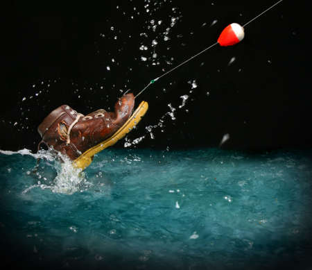 Catching an old shoe with a fishing pole. Splash of waterの写真素材