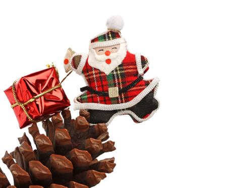 Christmas santa with gift box over a pine coneの写真素材