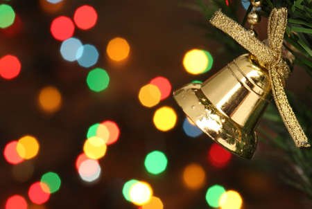 Christmas bell hanging on a branch tree, lights backgroundの写真素材