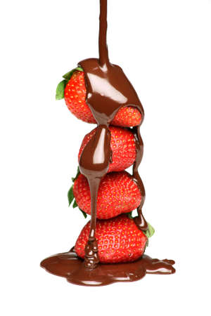 Pouring melted chocolate over four strawberriesの写真素材