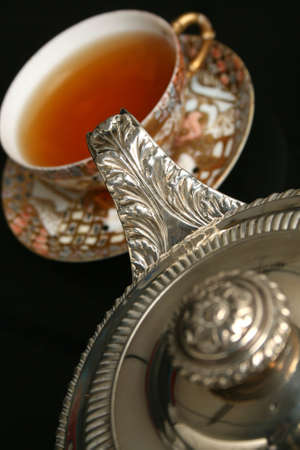Silver teapot pouring tea into antique chinese cupの写真素材