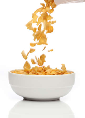 Pouring cornflakes into a bowl, over white background