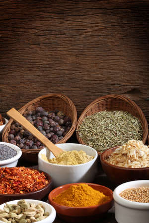 Various bowls of spices over wooden background  Colours and textures 