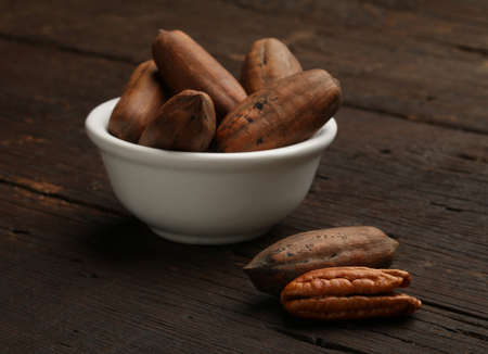 Group of pecan nuts in a bowl, over a wooden backgroundの写真素材