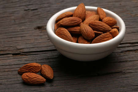 Group of delicious almonds in a bowl over a wooden backgroundの写真素材