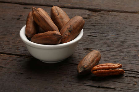 Group of pecan nuts in a bowl, over a wooden backgroundの写真素材