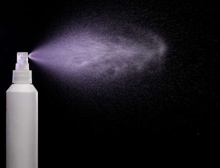 Spraying product in spray bottle over black backgroundの写真素材