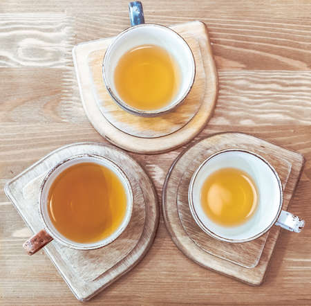 Three cups with tea on a stand on a wooden tableの写真素材
