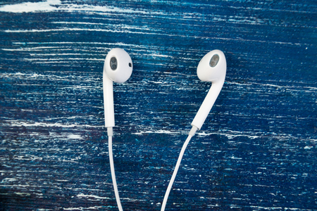 White little headphones on blue jeans wooden isolated backgroundの写真素材