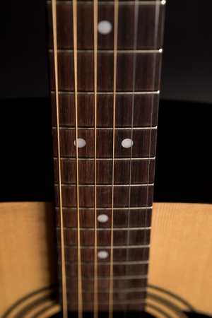 Part of a wooden acoustic guitar on a black isolated backgroundの写真素材