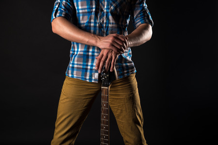 Music and art. The guitarist holds the electric guitar with his hands, on a black isolated background. Playing guitarの写真素材