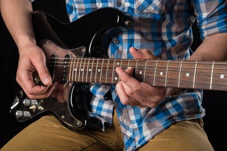 Music and art. Electric guitar in the hands of a guitarist, on a black isolated background. Playing guitarの写真素材
