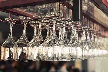 A row of clean empty wine glasses hang over the bar counterの写真素材