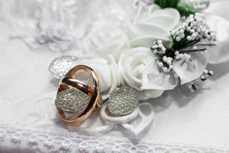 Gold wedding rings lie on a white pillowの写真素材