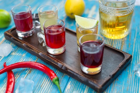 small glasses with colorful drinks on a wooden boardの写真素材
