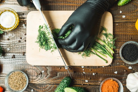 women's hands cut herbs, next to them are tomatoes, paprika, cucumbersの写真素材