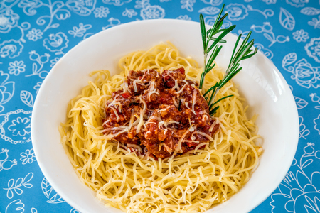 Noodles with minced meat and herbs on a white plateの写真素材