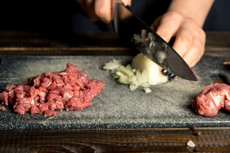 female hands cut onions, meat is near. Horizontal frameの写真素材