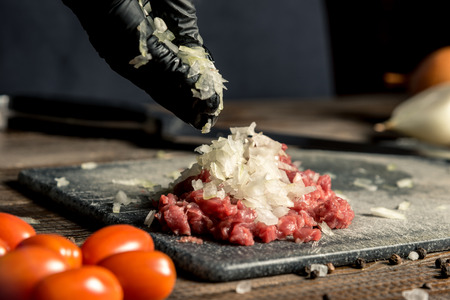 female hands mix onion and meat on a wooden board. Horizontal frameの写真素材