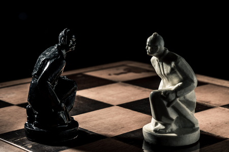 Chess board. Black beautiful handmade pawn stands in front of the white pawn of the opponent. Horizontal frameの写真素材