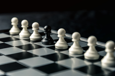 Chess board. Among the white pawns standing in a row is the black pawn of the enemy. Horizontal frameの写真素材