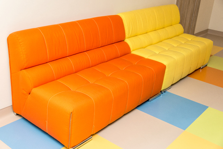 Two multicolored yellow and orange sofas on a color floor. Horizontal frameの写真素材