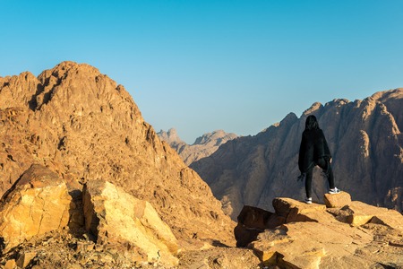 girl in black poncho stands on the background of mountains. Horizontal frameの写真素材