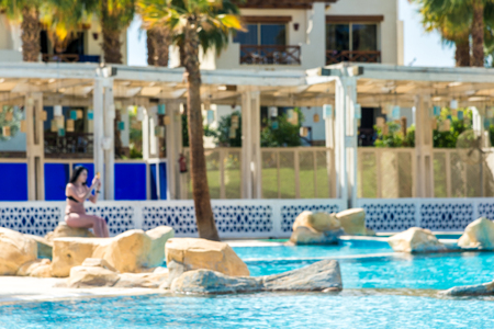 The interior of the hotel for recreation. Blue water pool, palm trees and sun beds out of focus....