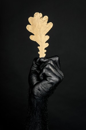 the hand is completely black paint with a yellow oak leaf. Vertical frameの写真素材