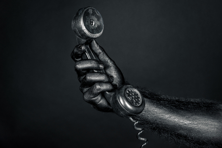the hand is completely in black paint holding a black telephone. Horizontal frameの写真素材