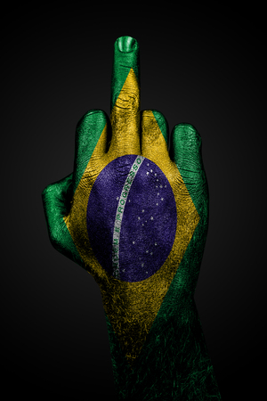 A hand with a painted flag of Brazil shows the middle finger, a sign of aggression, against a dark background. Vertical frameの写真素材