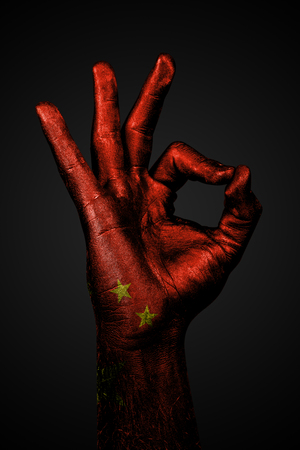A hand with the painted flag of china shows an OK sign on a dark background. Vertical frameの写真素材