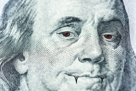 Benjamin Franklin's face with red eyes and fangs like a vampire, a symbol of a bloodsucker, pumping out money, inflation, dependence on currency, close-up. Horizontal frameの写真素材