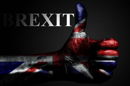 A hand with a painted UK flag shows a "thumbs up" sign and the inscription BREXIT, a symbol of success, readiness, and a task performed on a dark background. Horizontal frameの写真素材