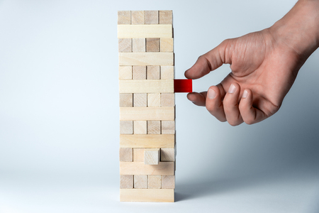Male hand puts a cube on the tower of wooden cubes, as a symbol of support, teamwork and business developmentの写真素材