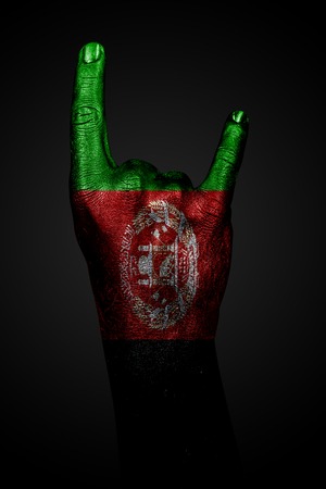 A hand with a drawn Afghanistan flag shows a goat sign, a symbol of mainstream, metal and rock music, on a dark background. Vertical frameの写真素材