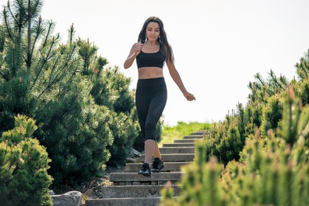 Slender beautiful girl with dark hair runs down the stairs, a symbol of healthy lifestyles, a strong leader and healthy competition. Horizontal frameの写真素材