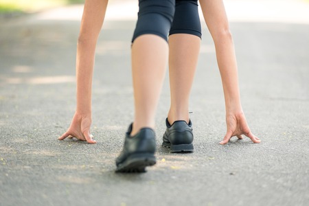 Female legs and hands put on the asphalt close-up, symbol of the start before the run, strong...