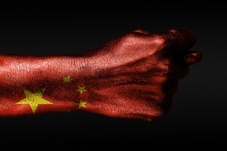 A hand with a painted China flag shows a fig, a sign of aggression, disagreement, a dispute on a dark background. Horizontal frameの写真素材