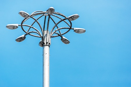 Tall old city lamppost stands against blue sky. Horizontal frame