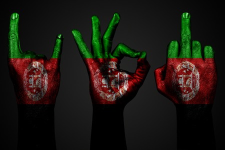a set of three hands with a painted flag Afghanistan show middle finger, goat and Okay, a sign of aggression, protest and approval on a dark background. Horizontal frameの写真素材